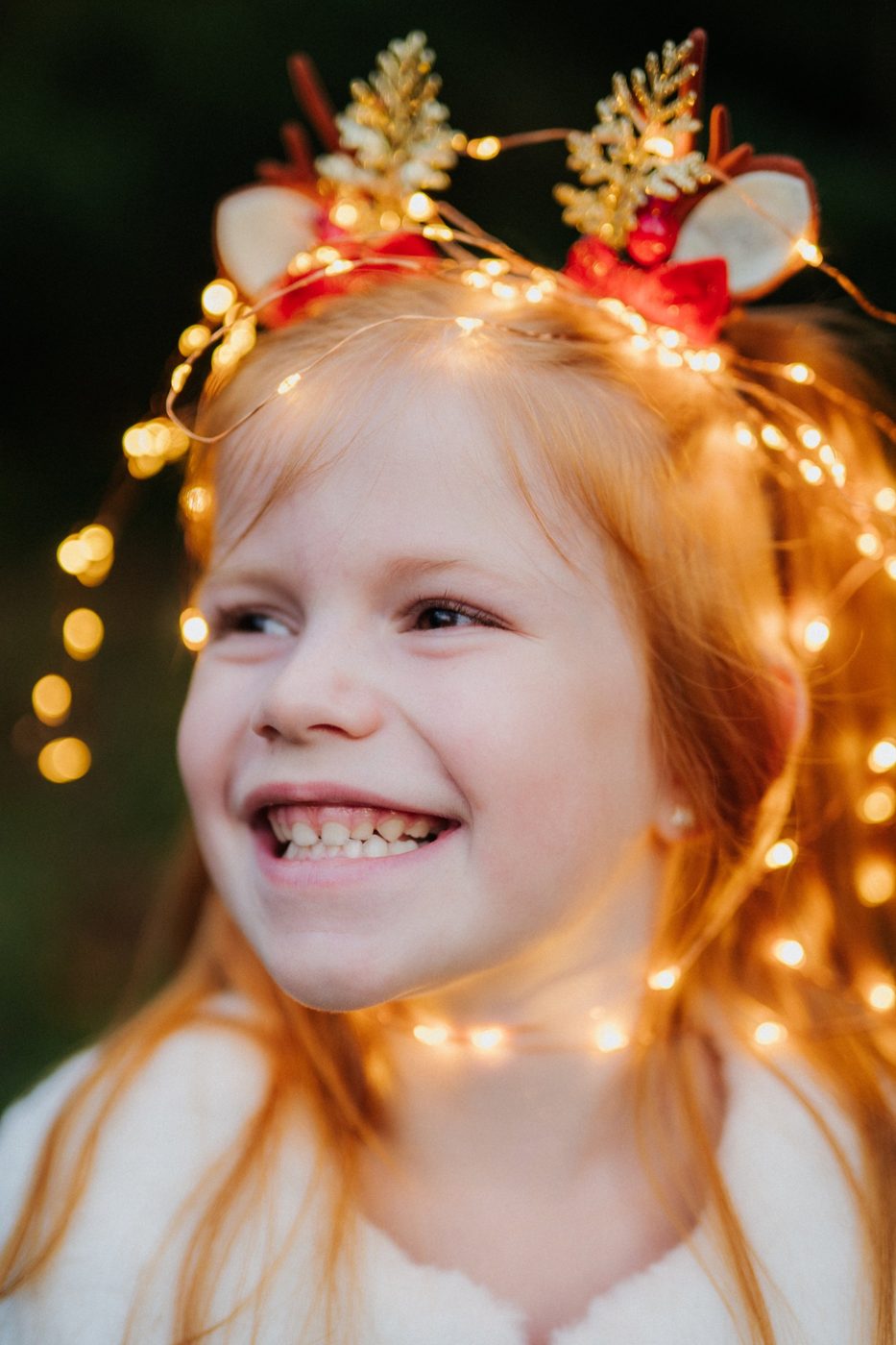 Petite fille rousse qui rit, des lumières dans les cheveux, capsules de Noël par Cathy Line