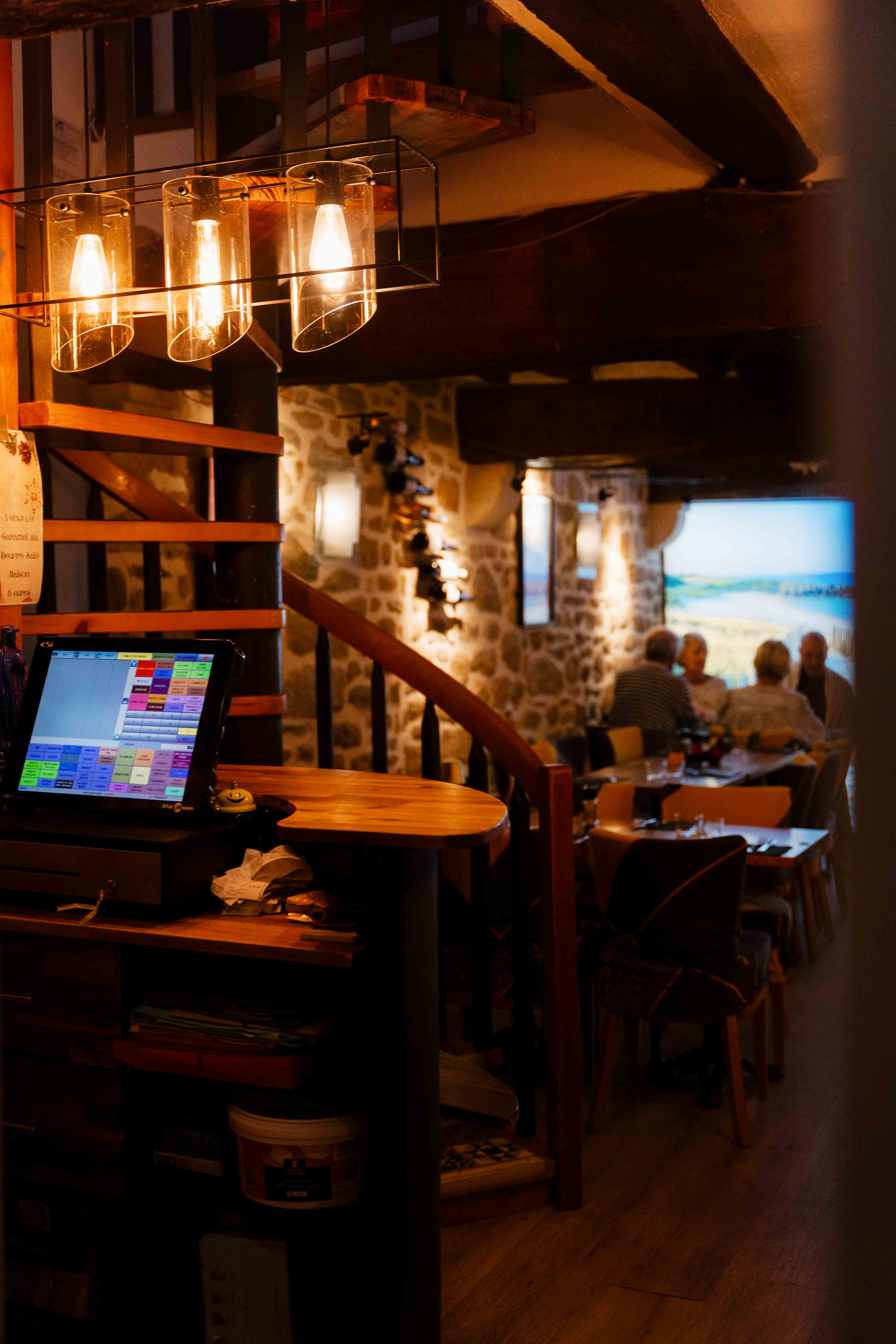 La salle aux murs de pierre de la Crêperie du Port, des clients attablés