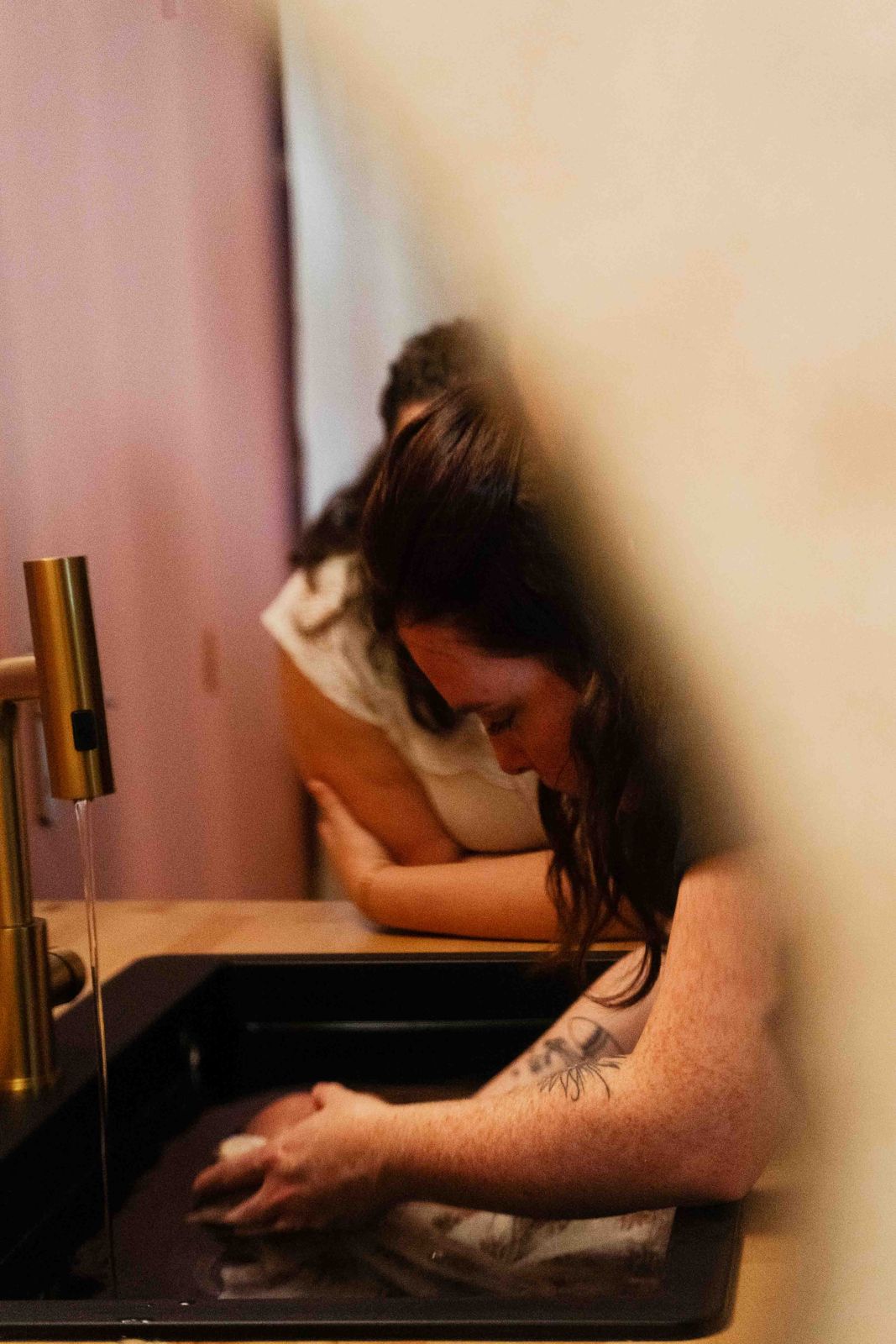 Anne-Laure penchée sur le bain, la maman tout près