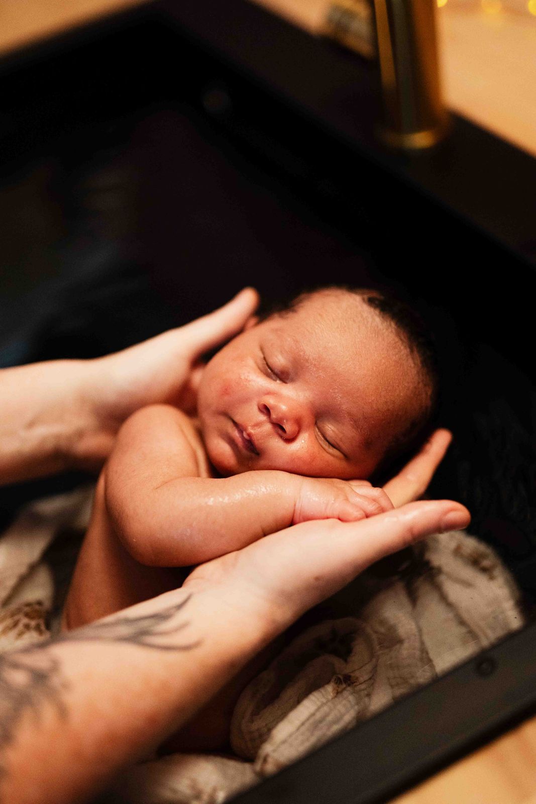 Bébé endormi, la tête posée dans les mains pendant le bain