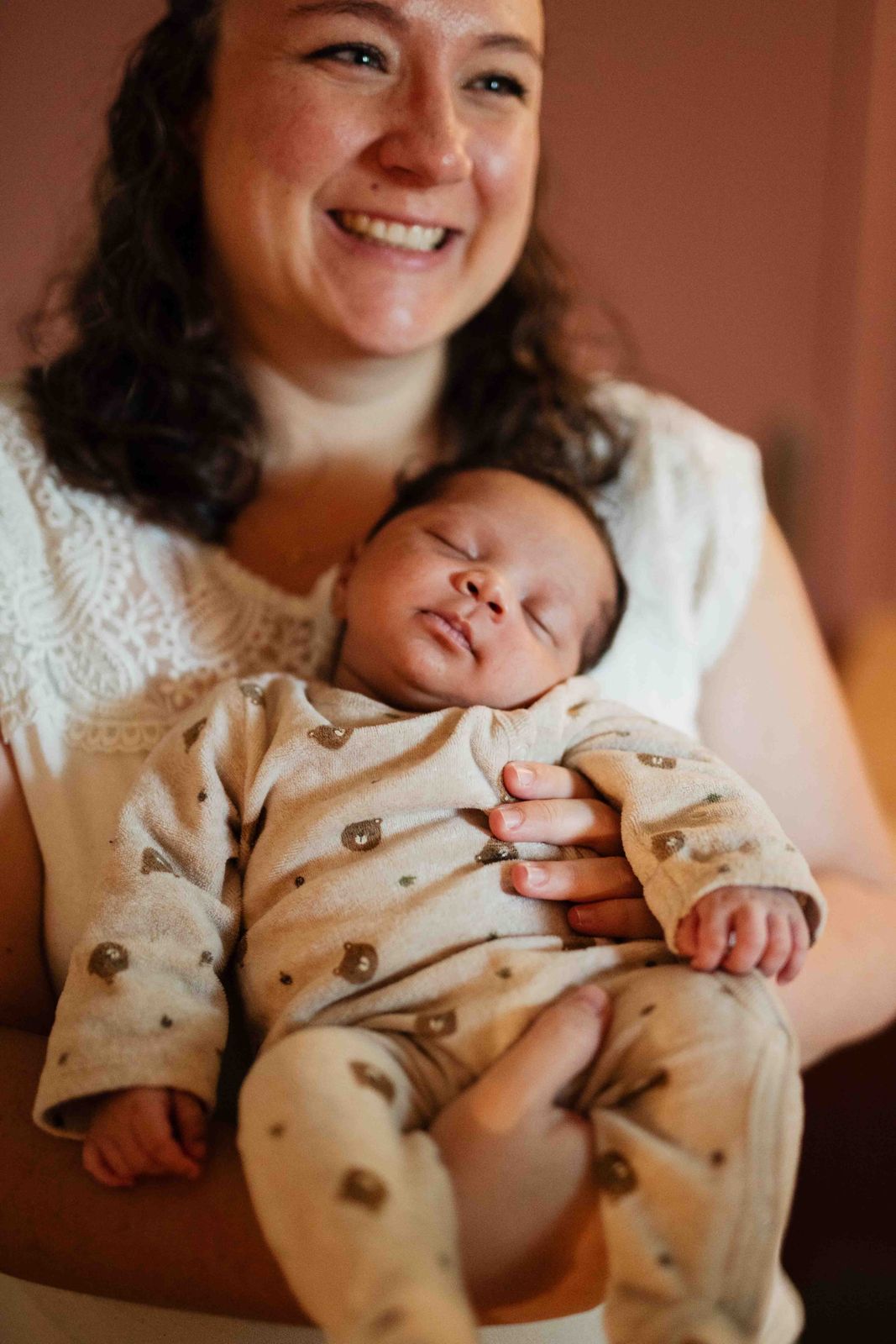 La maman sourit, son bébé endormi contre elle après le bain