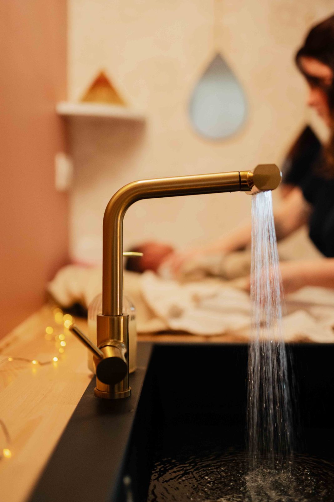 L'eau coule du robinet doré pendant qu'Anne-Laure prépare bébé